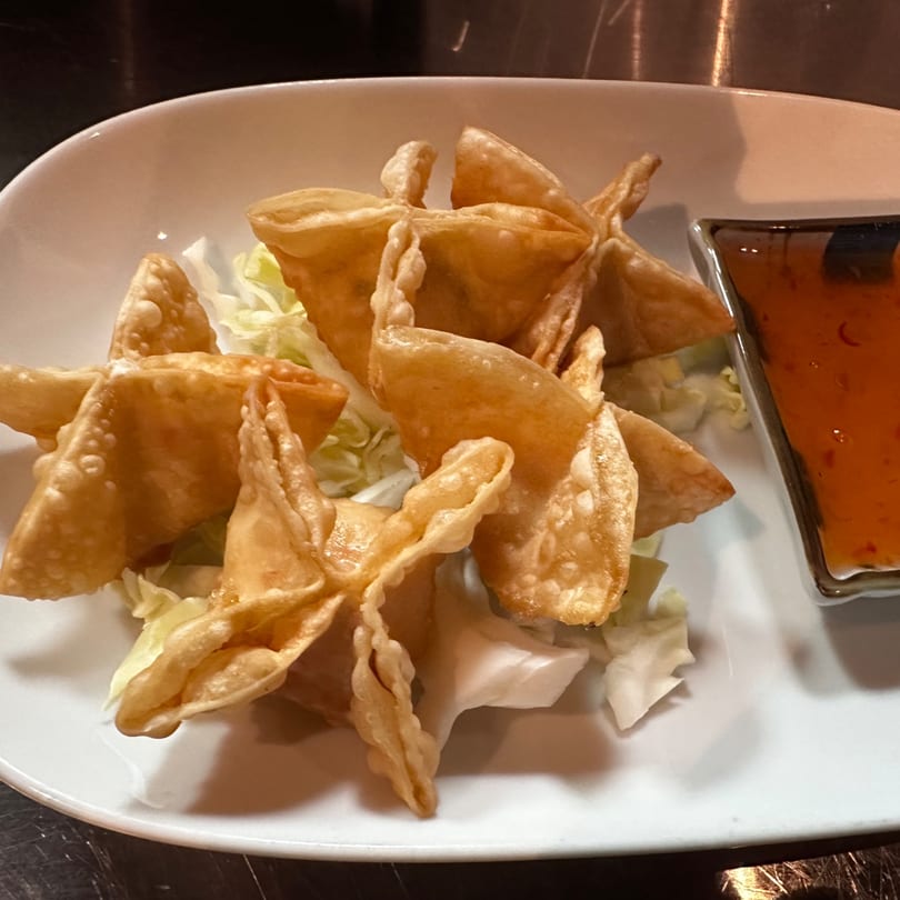 Golden-fried crab rangoon appetizers, shaped like stars, served with a side of sweet chili dipping sauce.