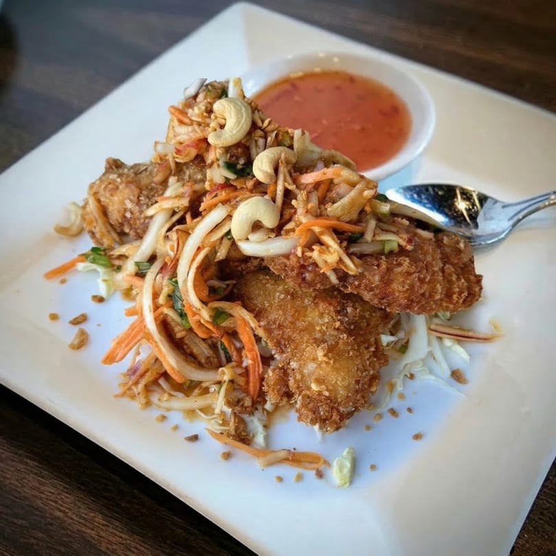 Crispy fried Thai chicken with shredded vegetables, cashews, and a side of dipping sauce.