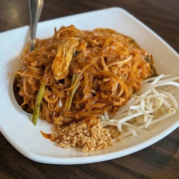 Sri Thai's Pad See Ew with chicken, bean sprouts, and crushed peanuts on a white plate.